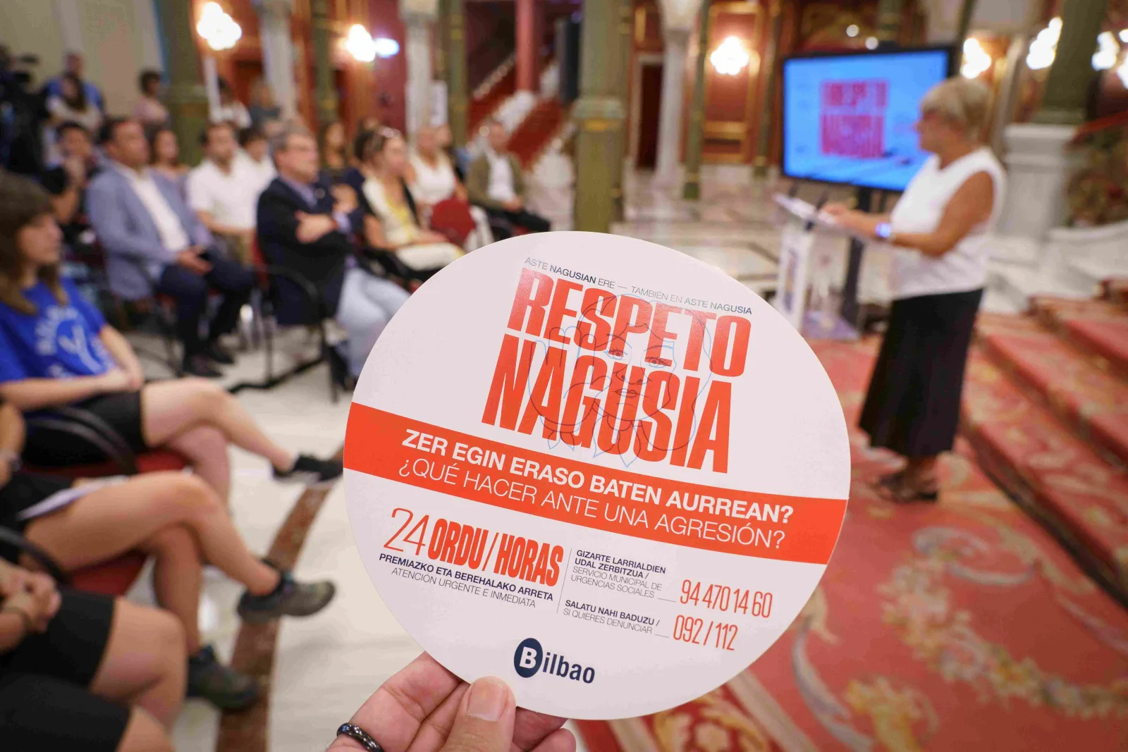 Una mano sostiene el disco de la campaña con el teléfono de atención 24 horas