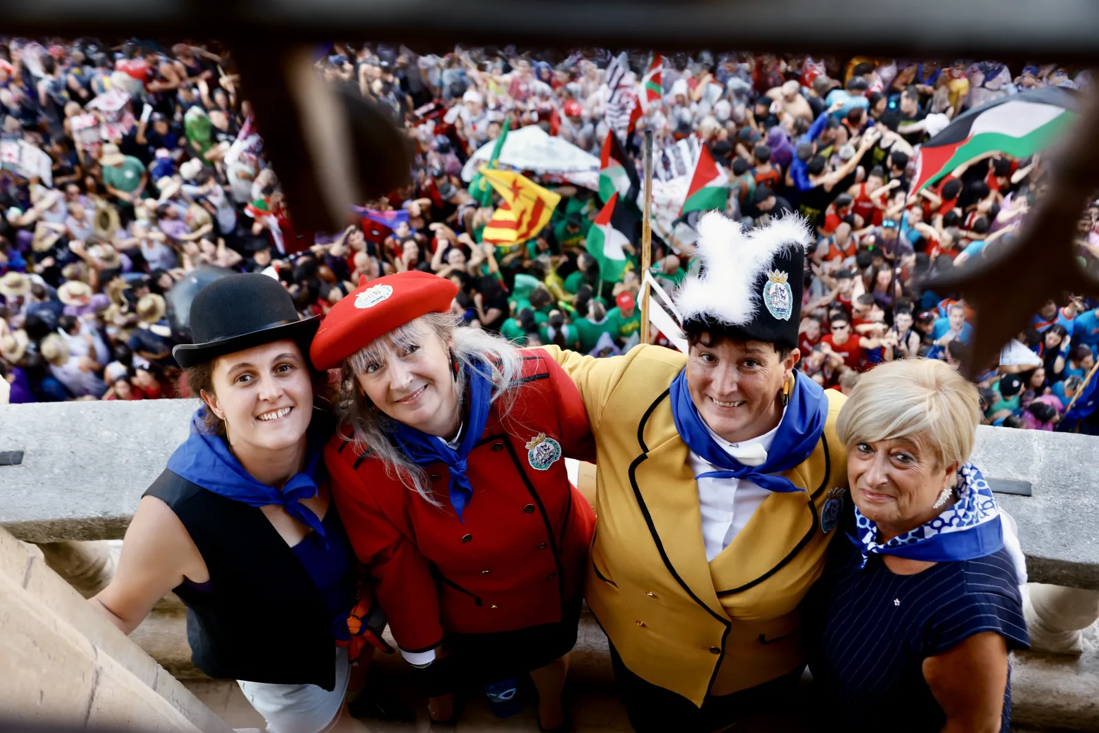 Cuatro miembros de las konpartsas posan con el Arenal lleno de gente al fondo