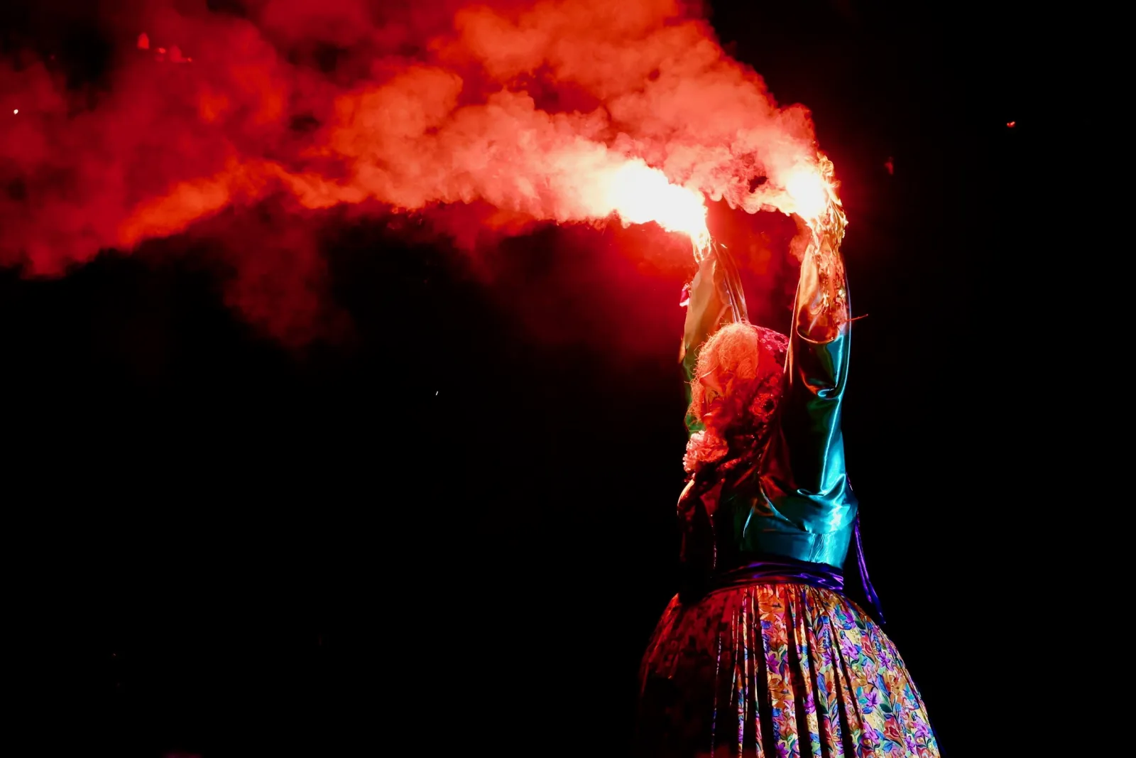 Marijaia envuelta en llamas: el fuego prende sus brazos alzados y una densa humareda roja se extiende por el cielo negro