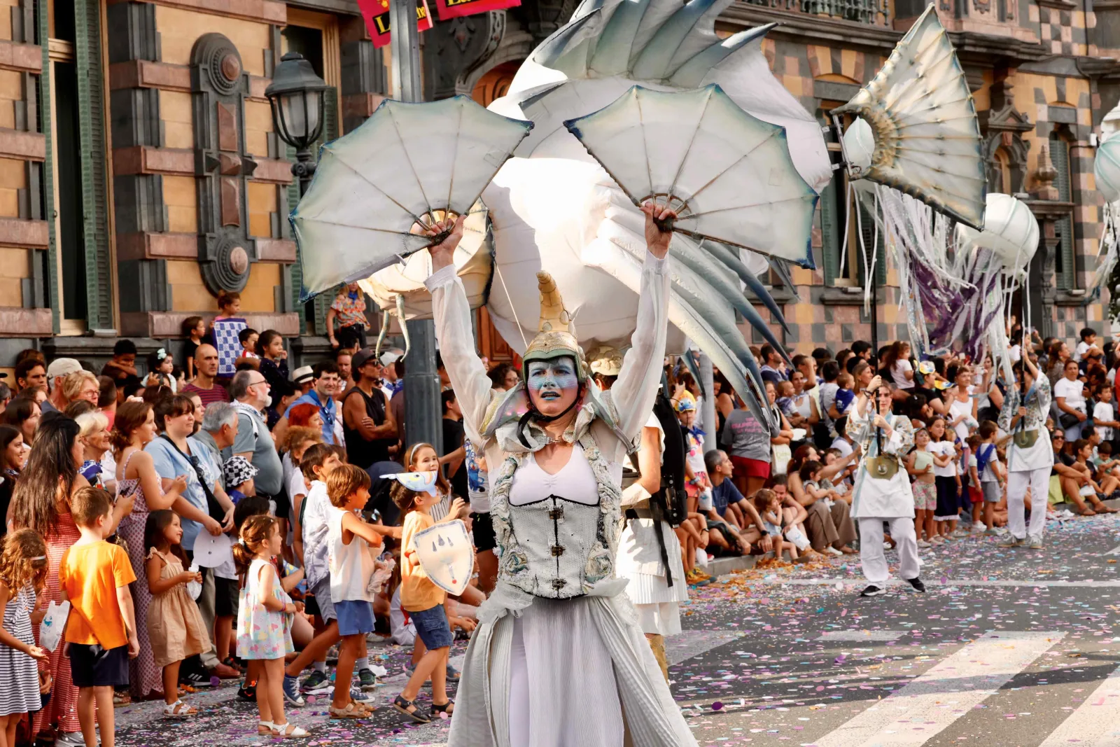 Uno de los personajes del cortejo del desfile, con una estructura desplegada a la espalda