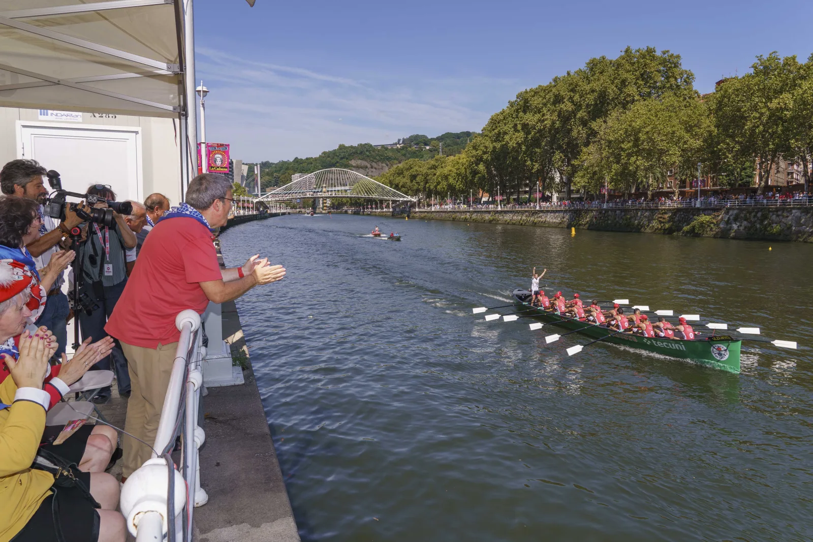 Una trainera avanza por la Ría de Bilbao con el público en las dos orillas