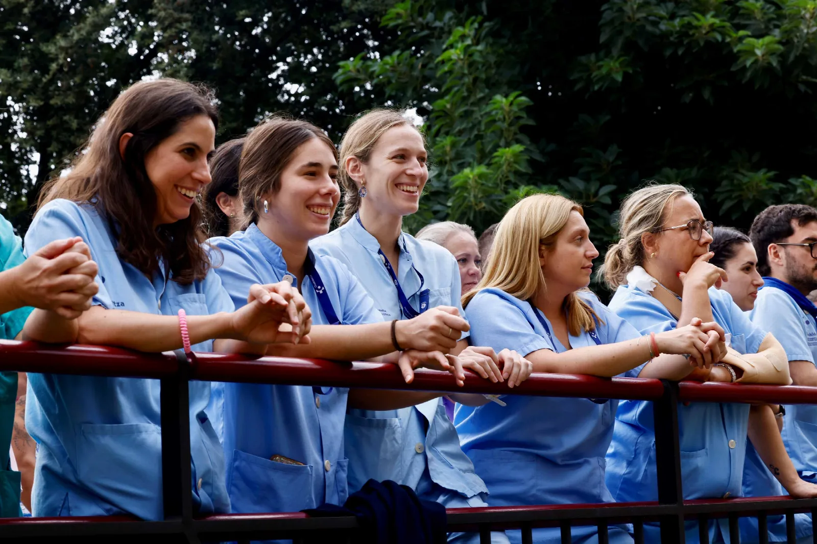 Un grupo de profesionales sanitarias con pijama azul mira la función apoyadas en una barandilla
