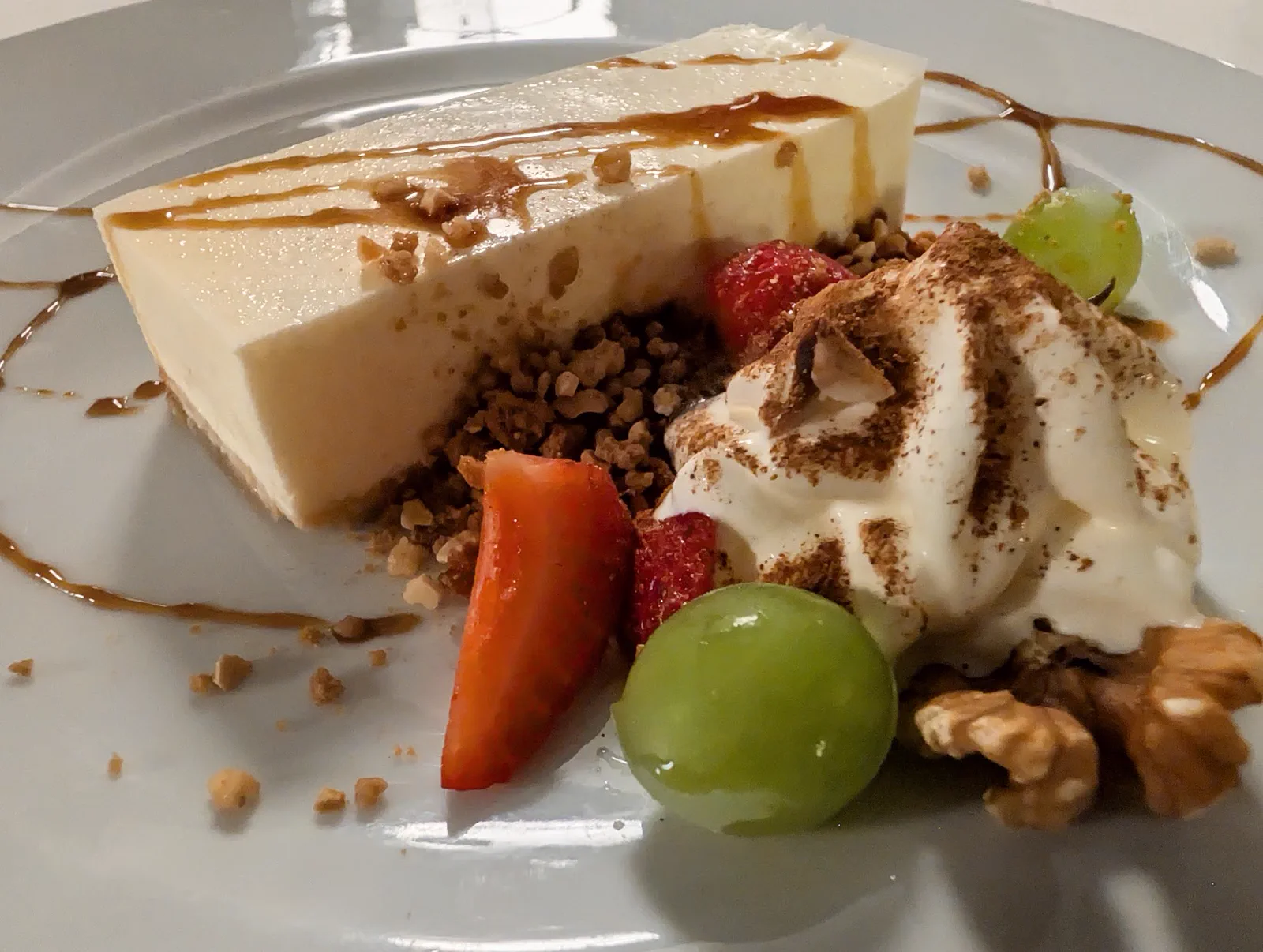 Porción de tarta de queso helada con crema, fresa, uva, nueces y crocanti, la tarta del día del menú del Asador Alaia