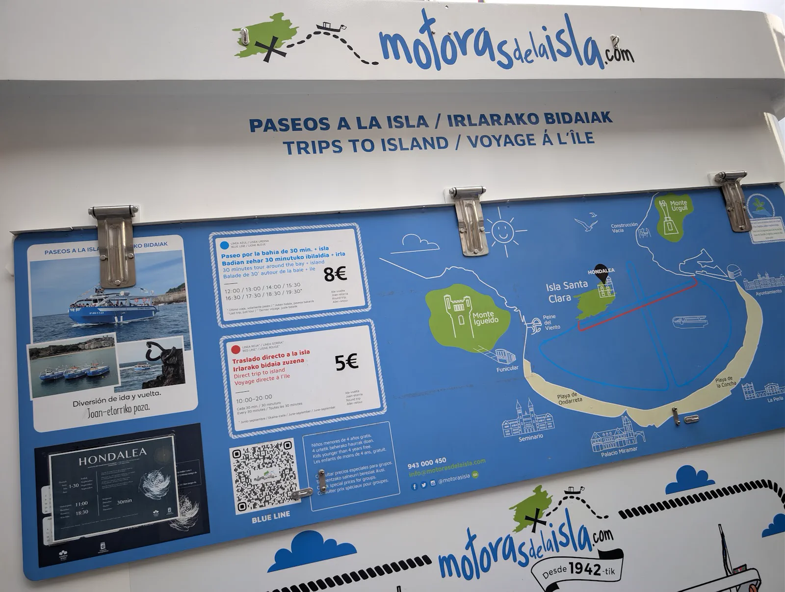 Cartel de tarifas de Motoras de la Isla con el mapa de la bahía, la línea azul del paseo de 30 minutos a 8 euros y la línea roja del traslado directo a la isla a 5 euros