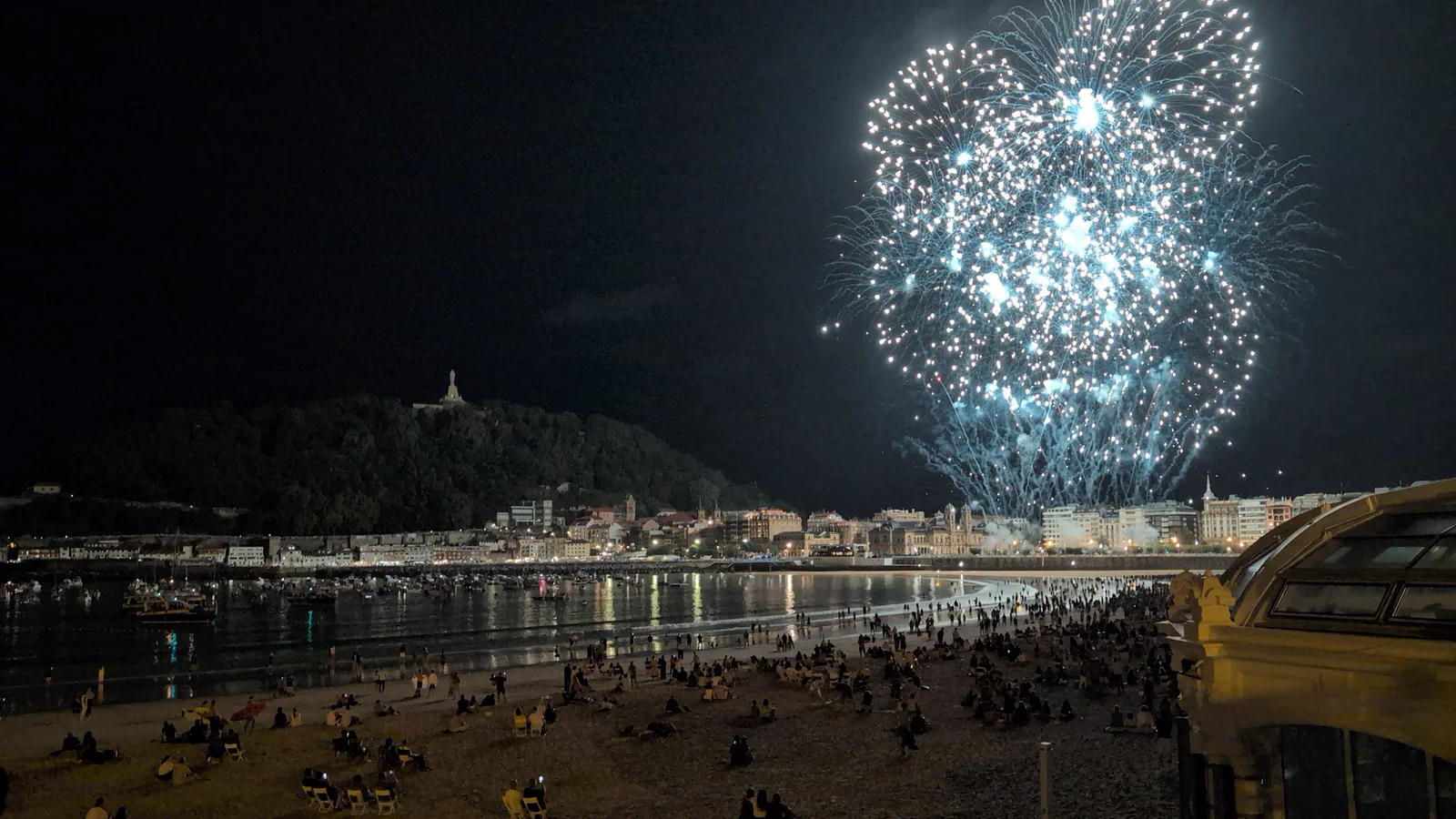 Palmera de fuegos artificiales blancos abriéndose sobre el centro de Donostia durante la tanda de Pirotecnia Tamarit