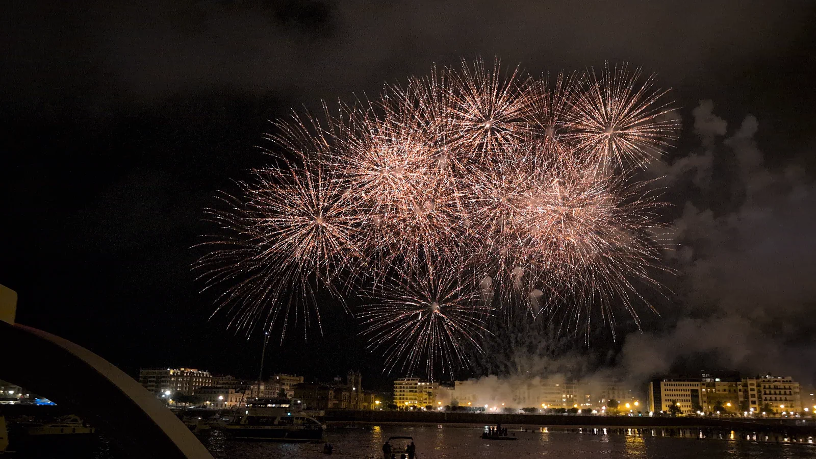 Racimo de fuegos rosados sobre el paseo, con el humo iluminado desde dentro