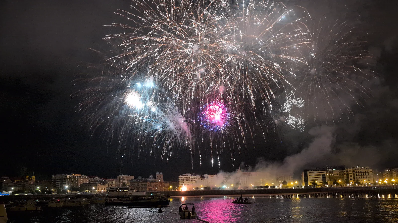 Estallidos magenta y blancos encadenados sobre la bahía, ya en la traca final