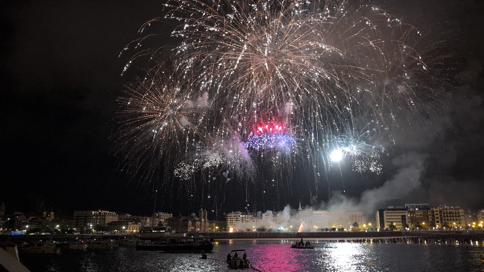 Gran estallido blanco y magenta que ilumina el agua de la bahía entera