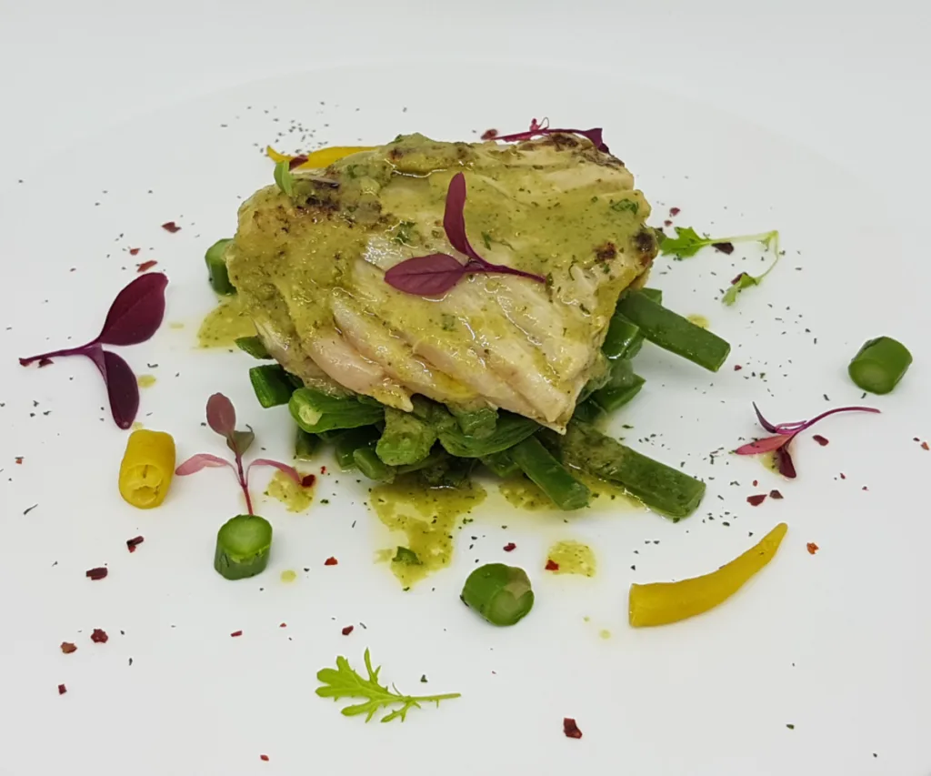 Ventresca a la plancha sobre un lecho de vainas y verduras, emplatada en Bokado Mikel Santamaría