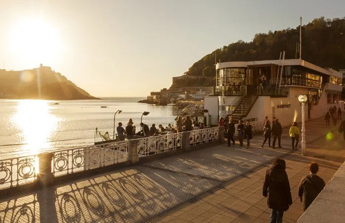 El edificio del GU y el paseo al atardecer, con la bahía de la Concha de Donostia al fondo