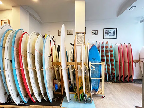 Decenas de tablas de surf de alquiler ordenadas en los expositores de la tienda de Hawaii Donostia