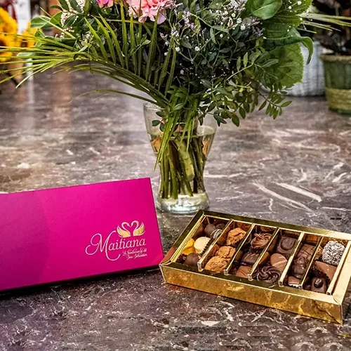 Caja de bombones artesanos de la Bombonería Maitiana junto a un ramo de flores