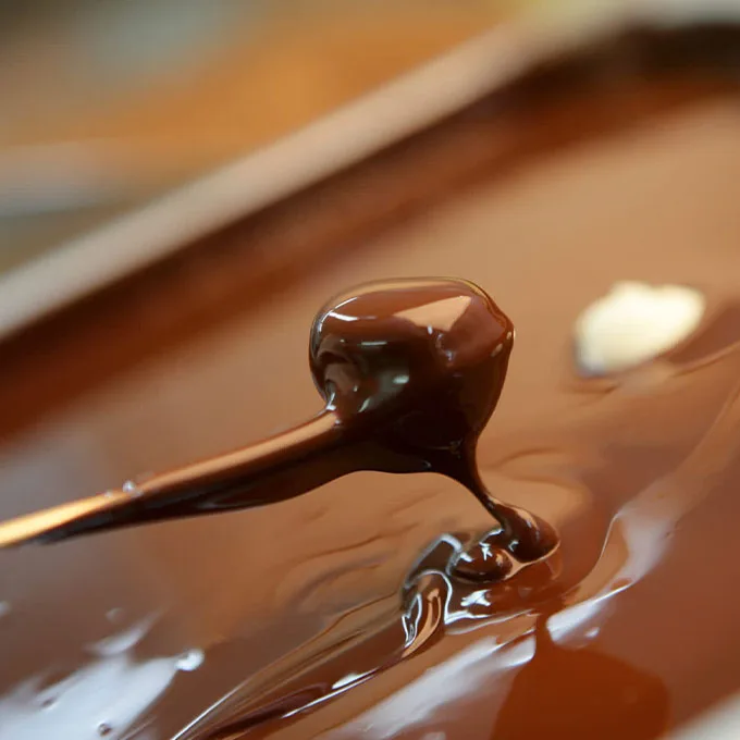 Un bombón bañándose en chocolate fundido brillante en el obrador de la Bombonería Maitiana
