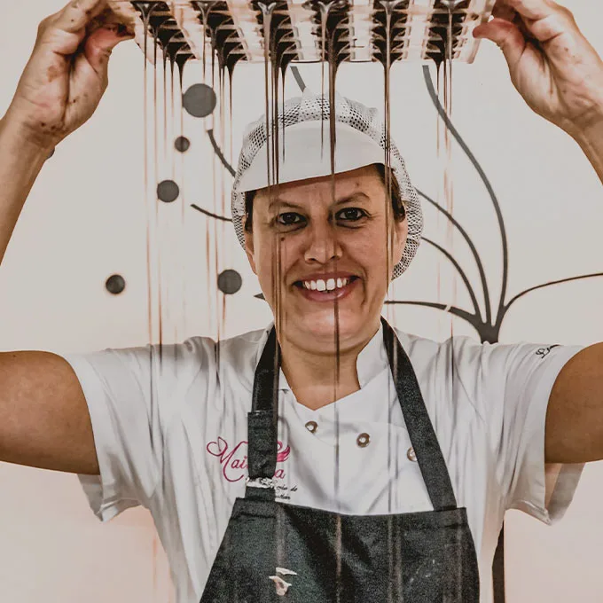 Una maestra chocolatera de Maitiana sonríe mientras cae un hilo de chocolate desde un molde