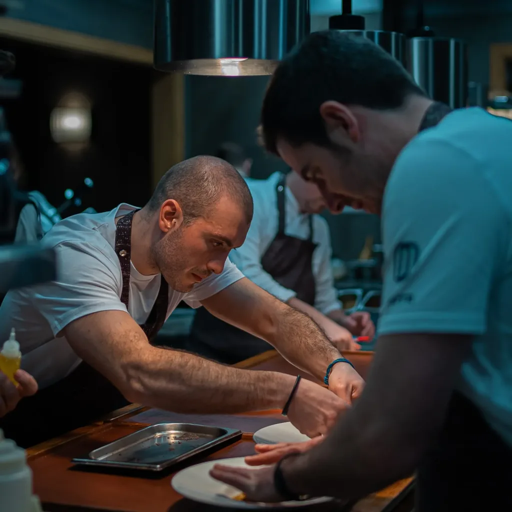 Cocineros de Narru emplatando en el pase de la cocina bajo la luz de las lámparas