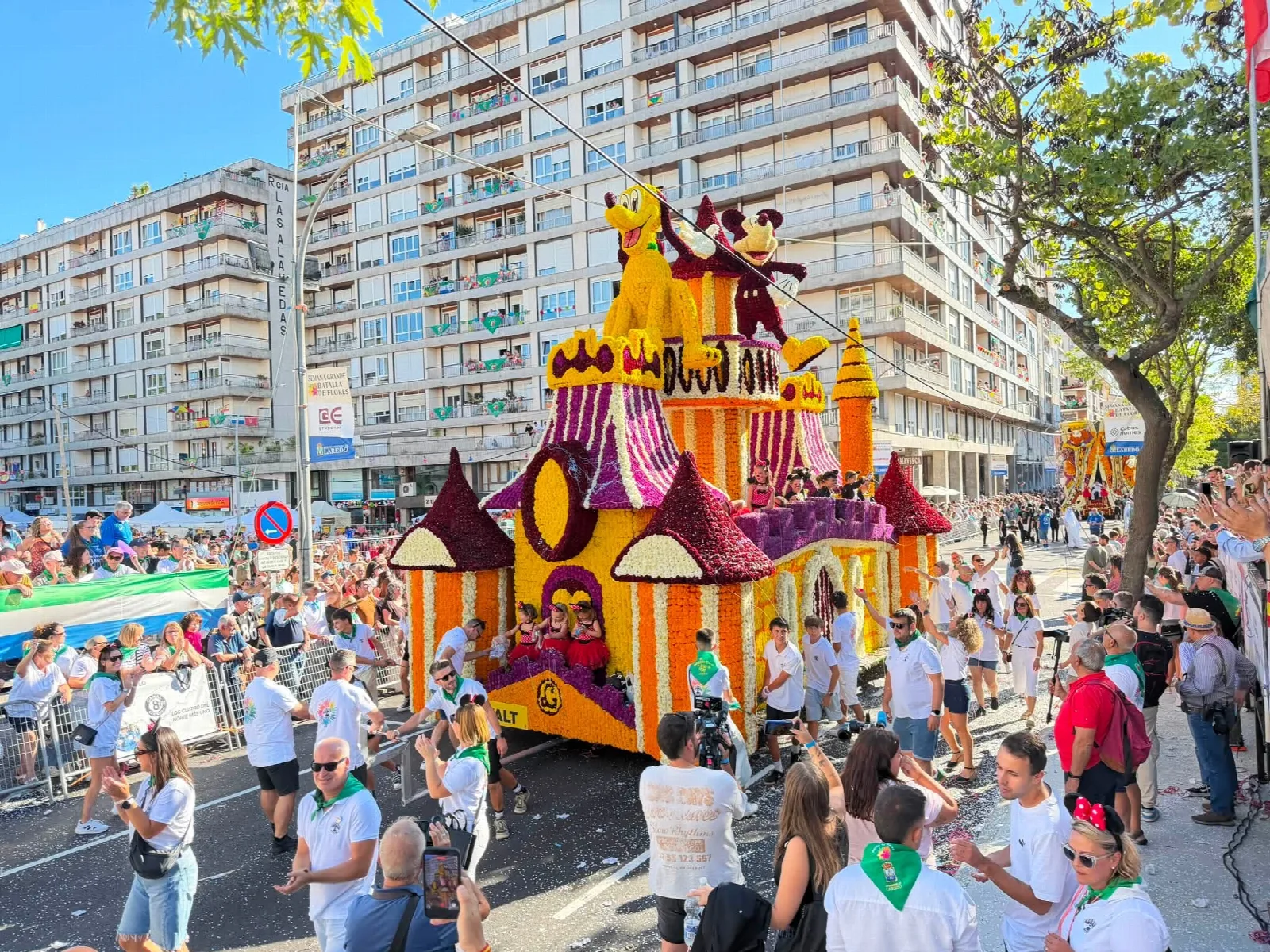 Carroza de flor con un castillo de cuento y figuras de personajes de dibujos animados clásicos, con la placa del título en la parte inferior